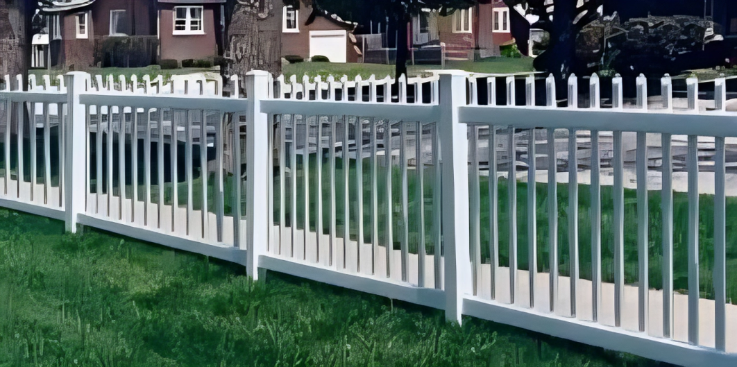 A white picket fence runs alongside a green lawn, with houses and a street visible in the background.
