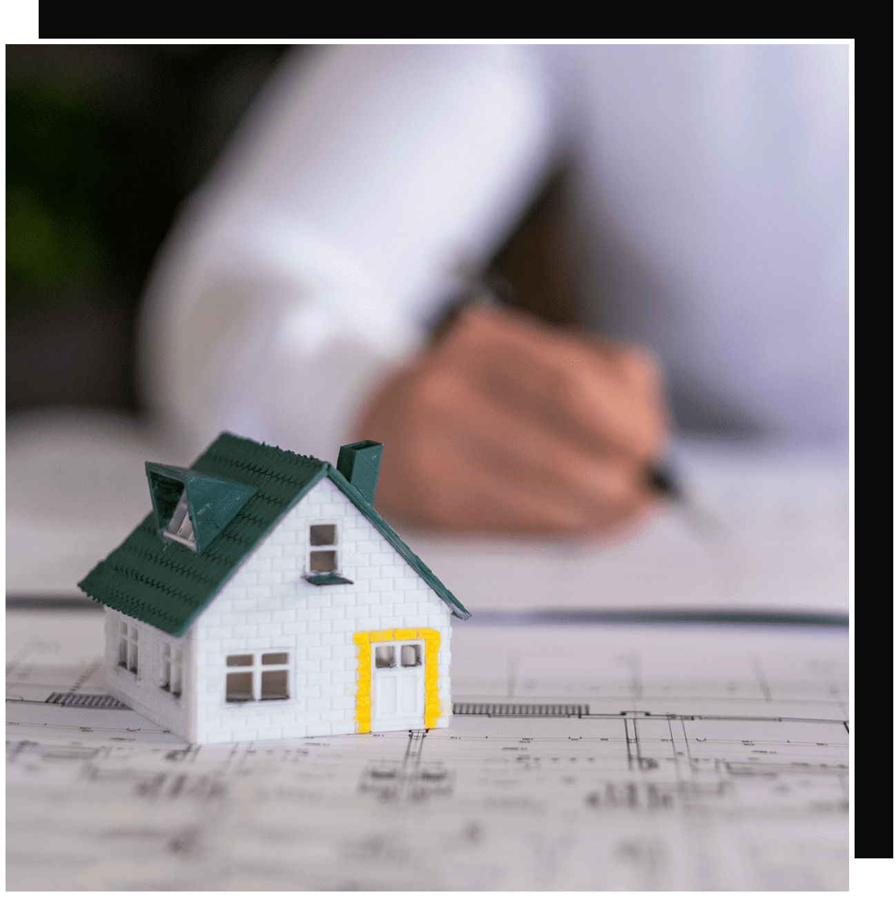 House model on blueprint, person signing documents