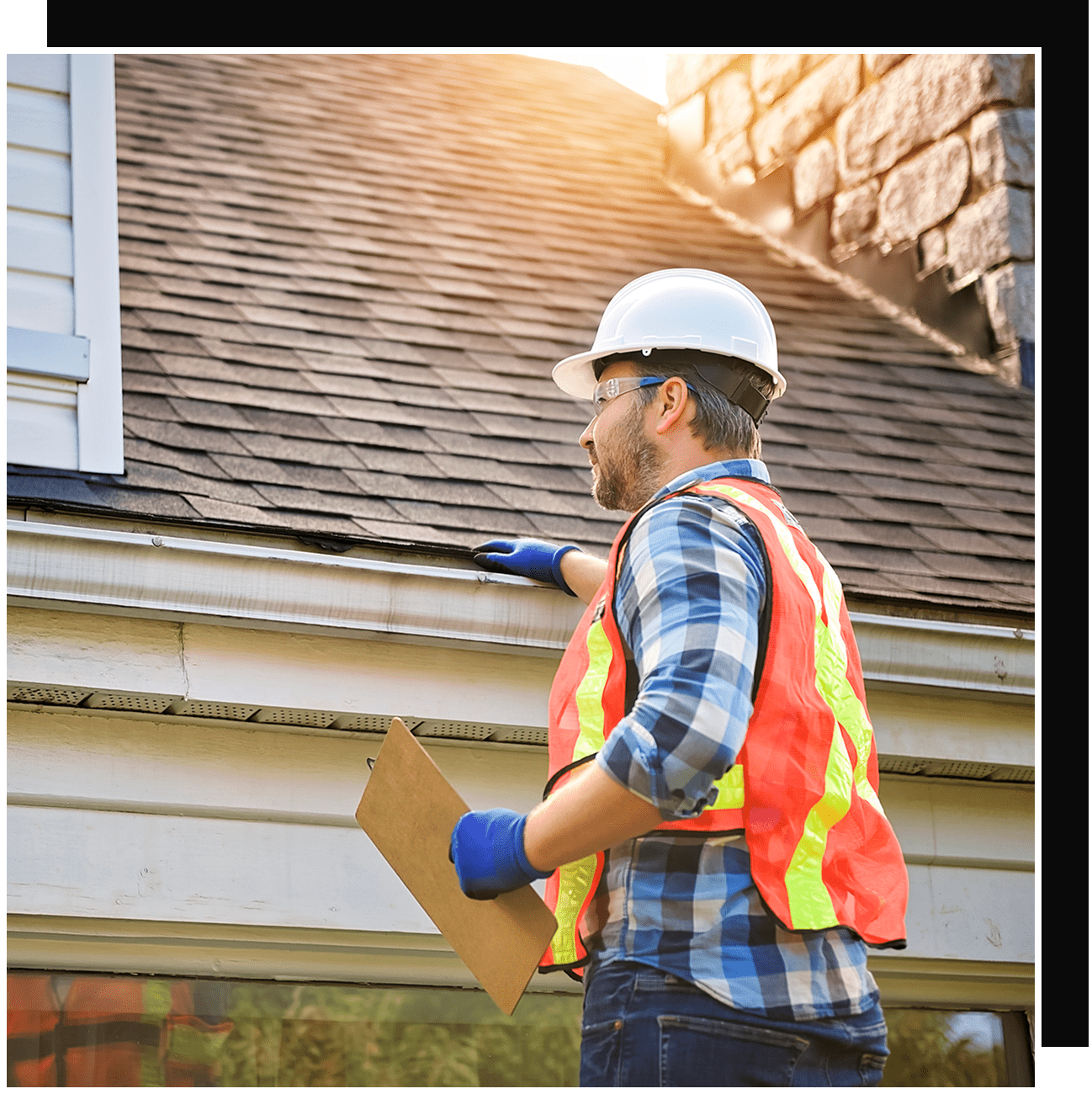 Construction worker inspecting house roof and gutter