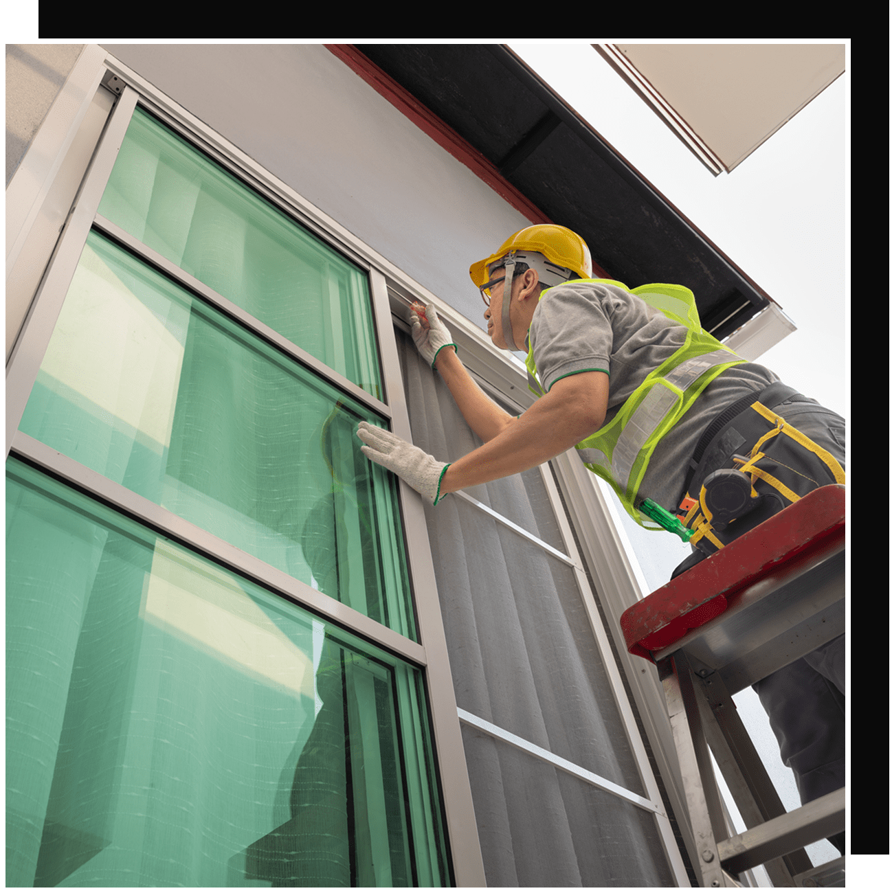 Worker cleaning exterior glass window on ladder