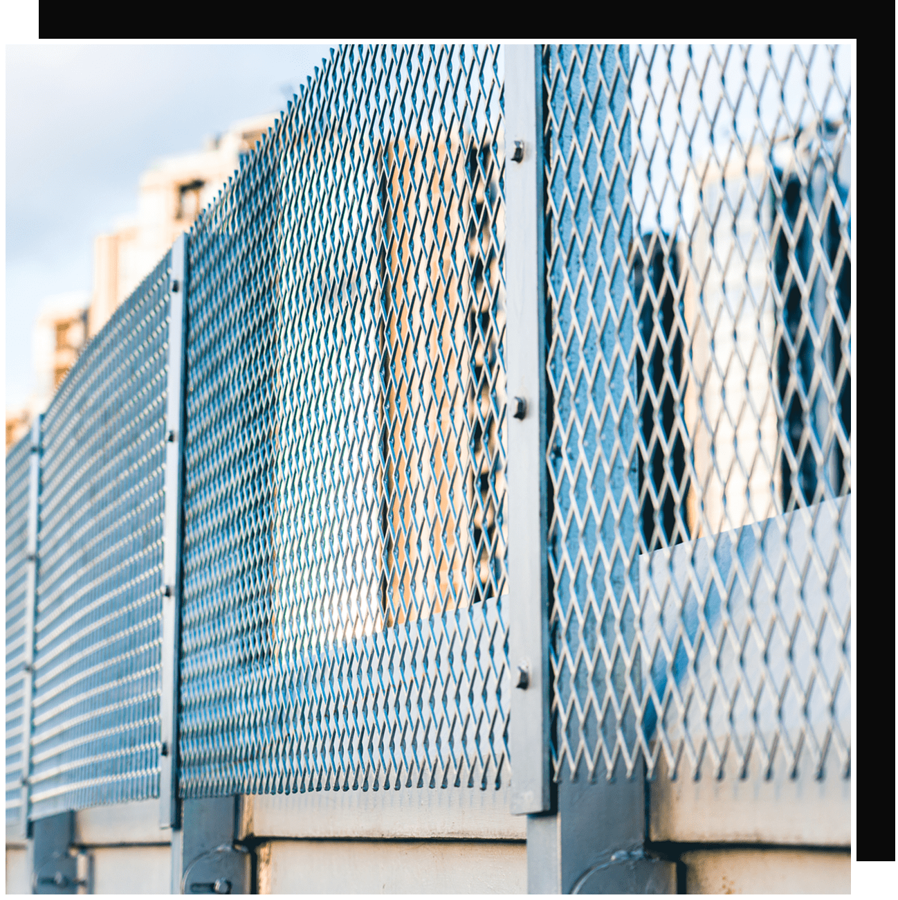 Blue metal diamond-pattern fence with buildings