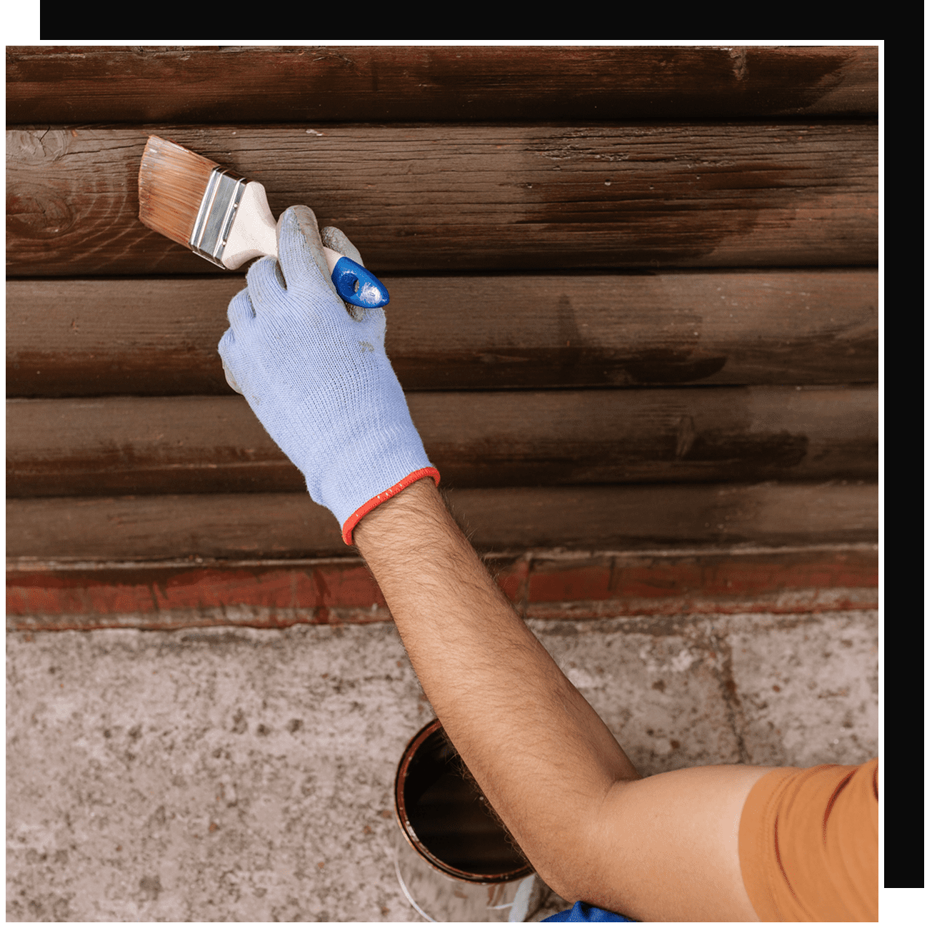 Gloved hand painting wooden siding with brush