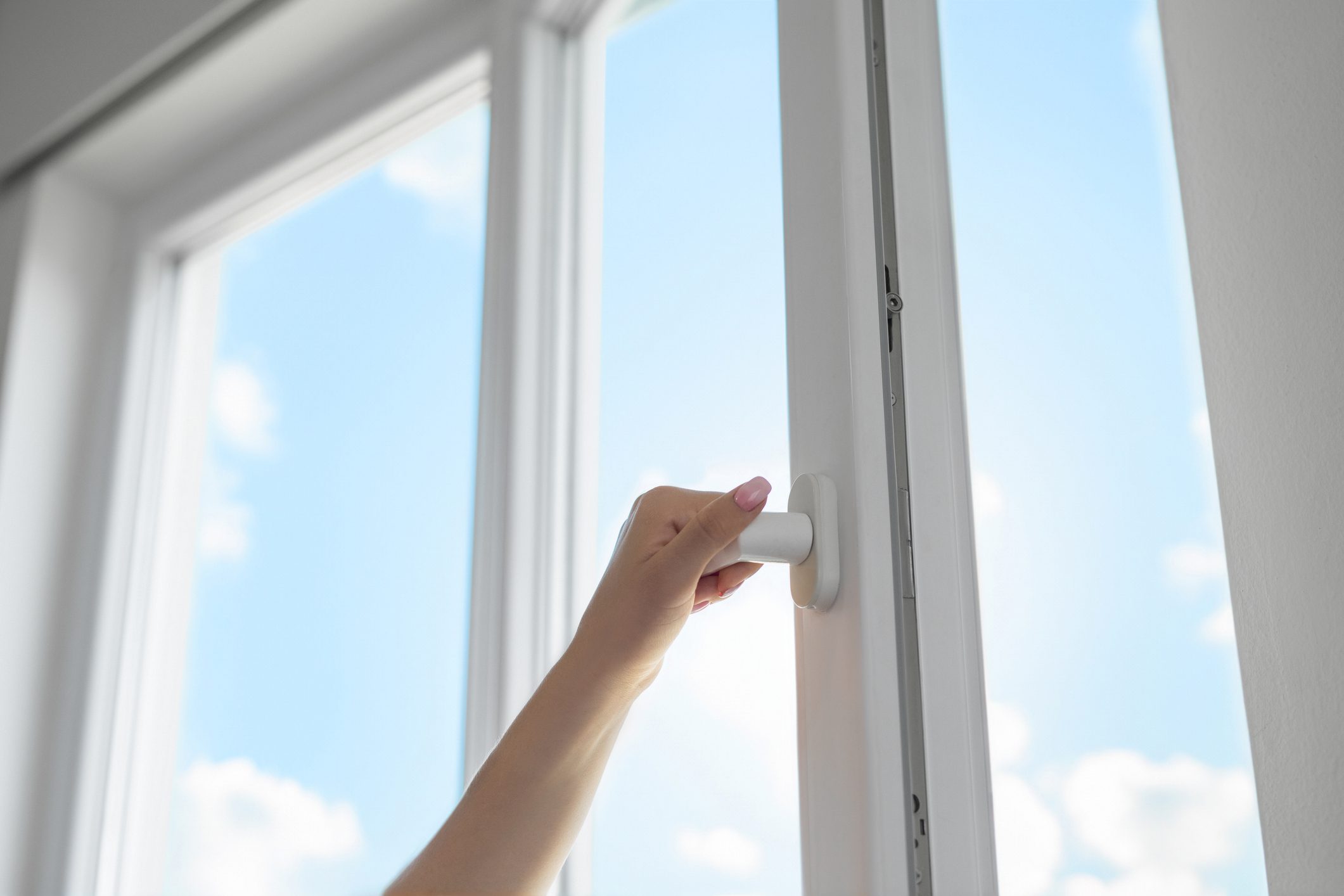 Hand opening window to blue sky