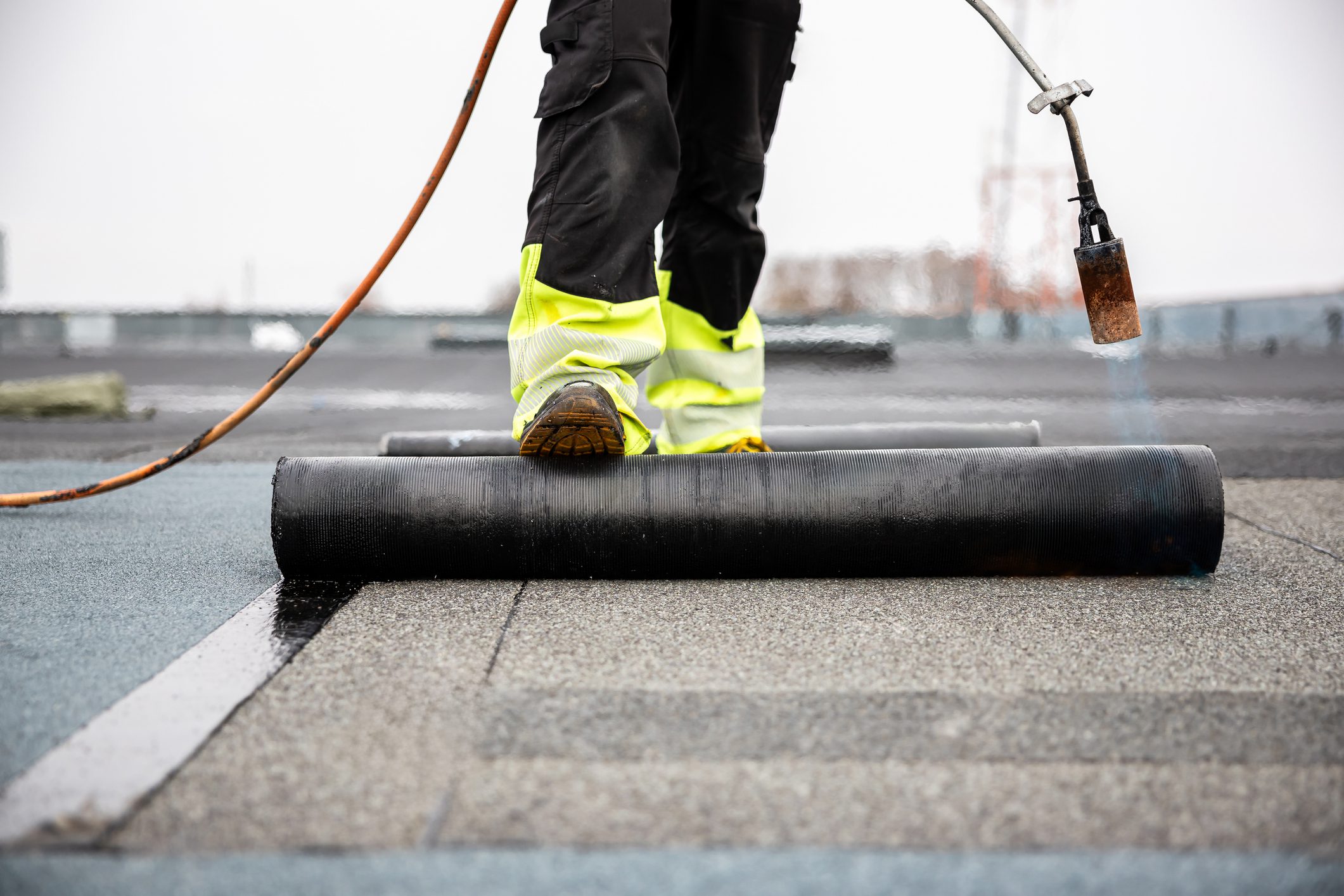 Worker installing torch-on rolled roofing membrane