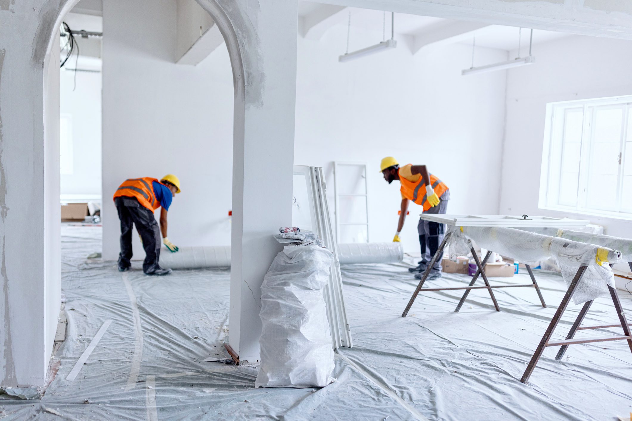 Construction workers covering floor with protective plastic