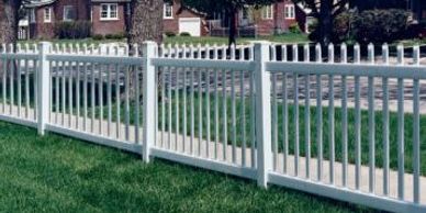 White vinyl fence along suburban green lawn