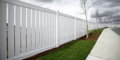 White vinyl fence along sidewalk with cloudy sky