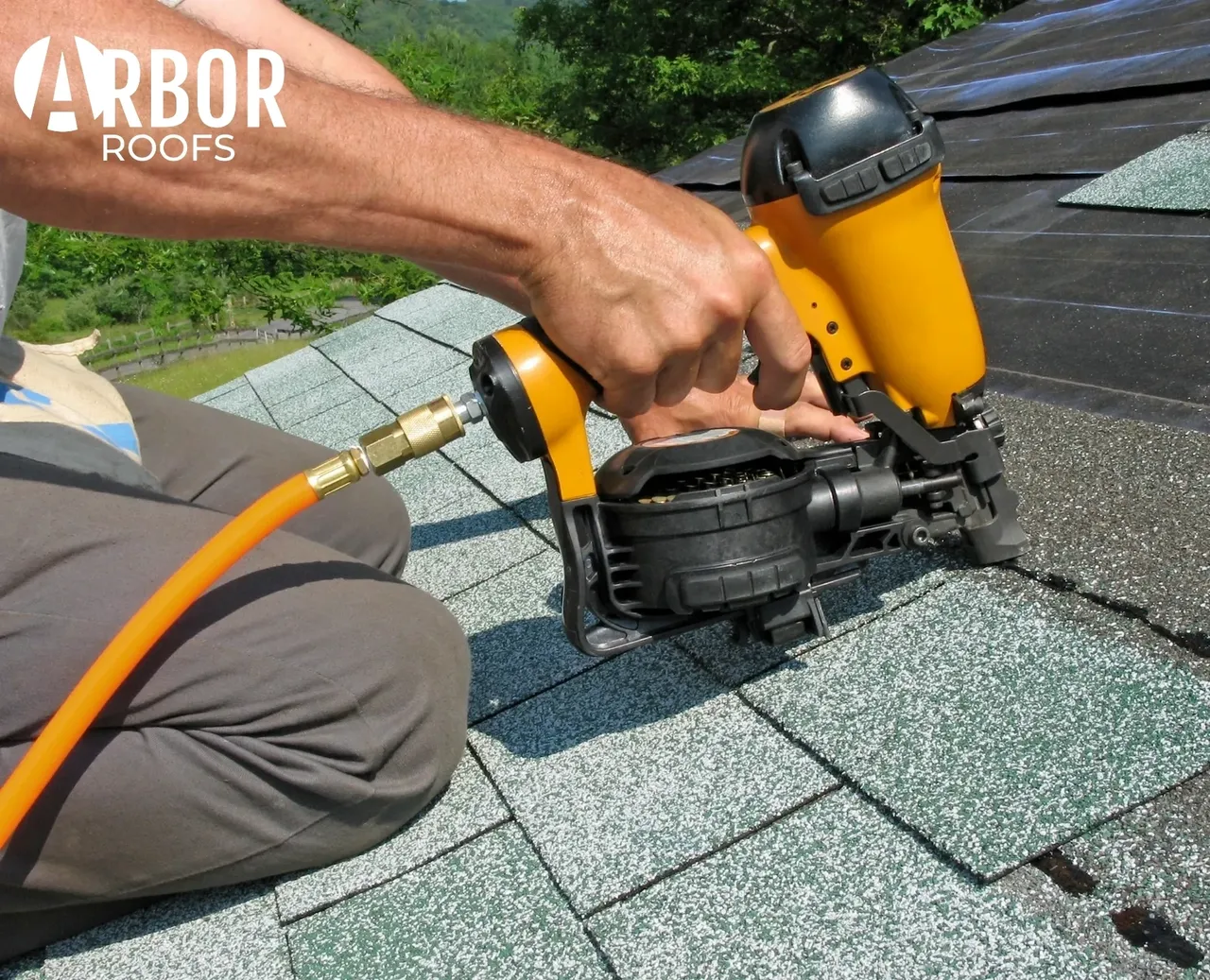 Contractor installing asphalt shingles with pneumatic nailer