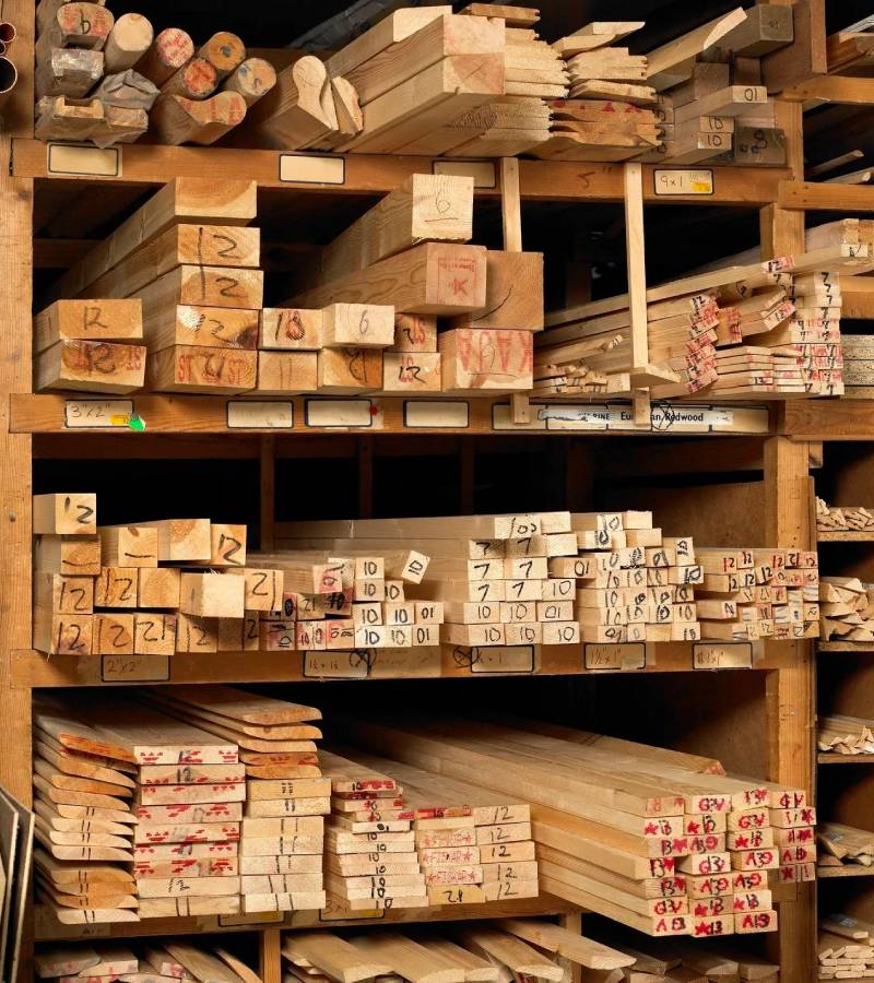 Stacked labeled lumber planks on wooden shelves