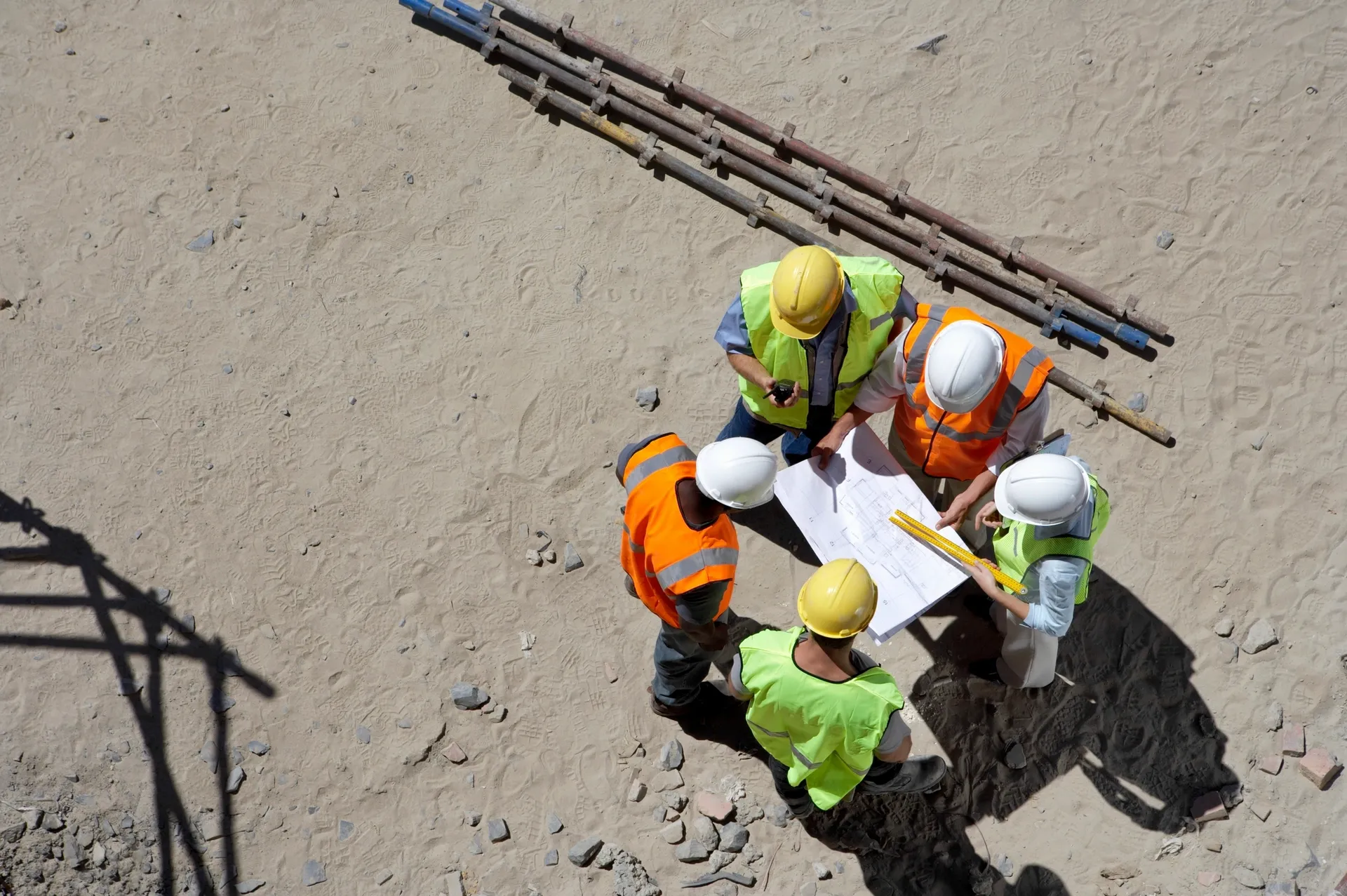 Construction crew reviewing plans on sandy site