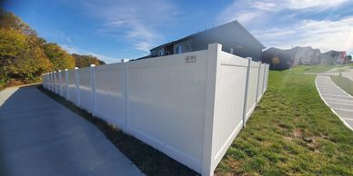 White vinyl privacy fence along suburban sidewalk