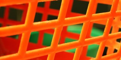Close-up orange plastic lattice basket with green background