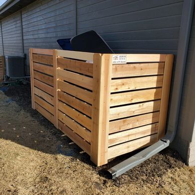 Wooden slatted outdoor trash bin enclosure