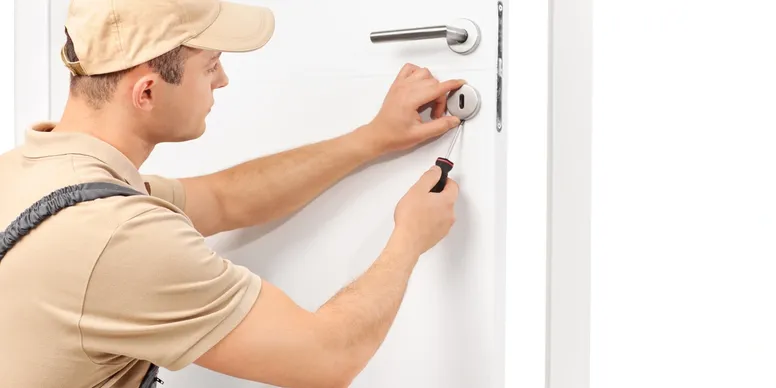 Locksmith repairing door lock with screwdriver