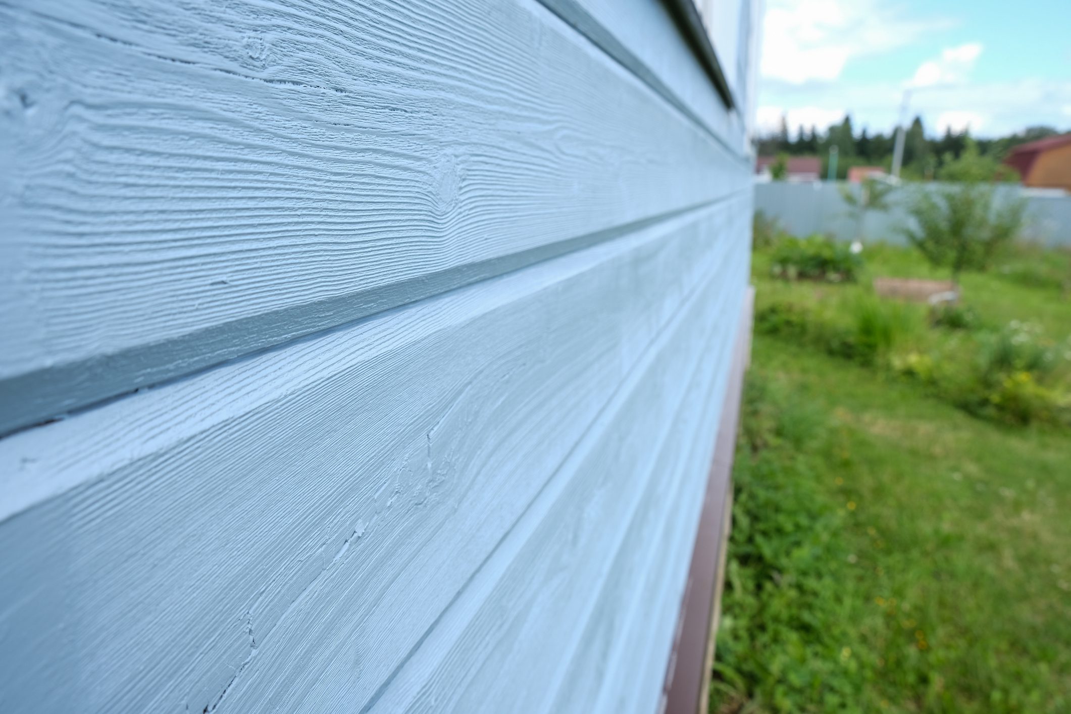 Blue wooden panels of a small frame country house painted in blue.