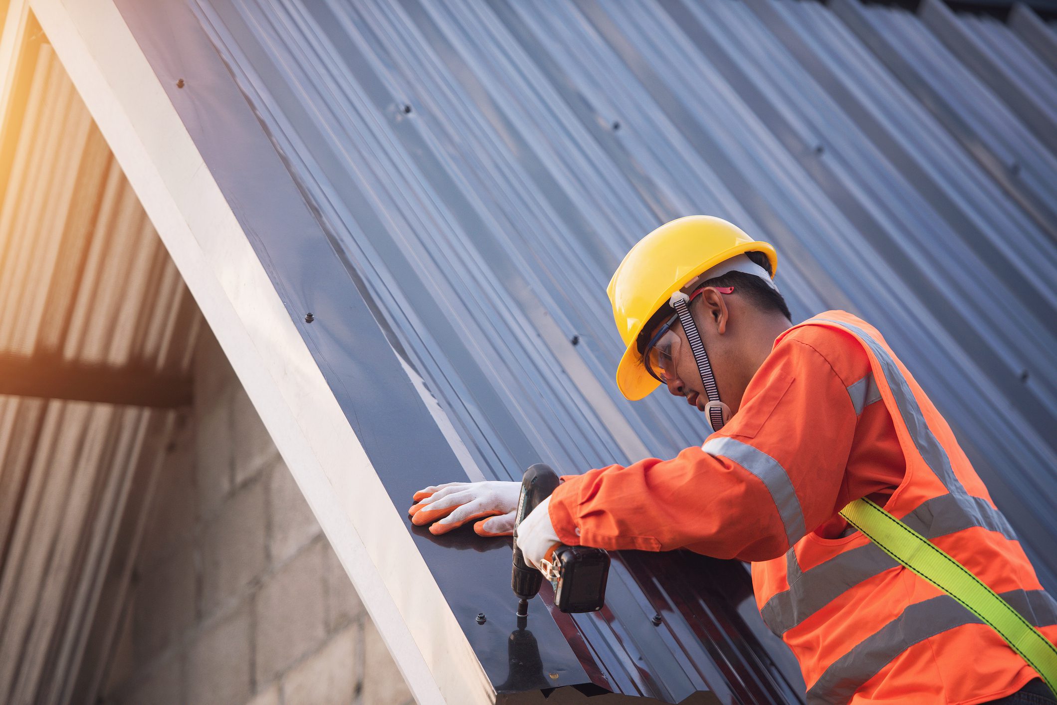 Construction worker install new roof,Roofing tools,Electric drill used on new roofs with Metal Sheet.Roof repair, a Specialist in Roof Forming,