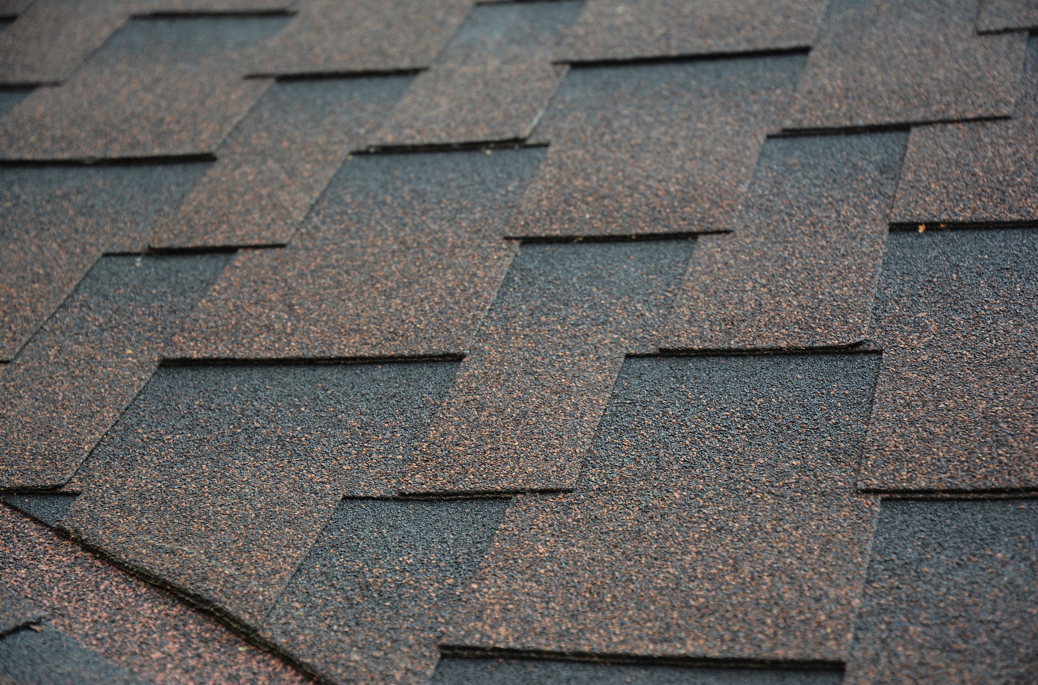 A close-up of an open roof valley covered with asphalt shingles. Waterproofing problem roofing area that can cause roof leaks.