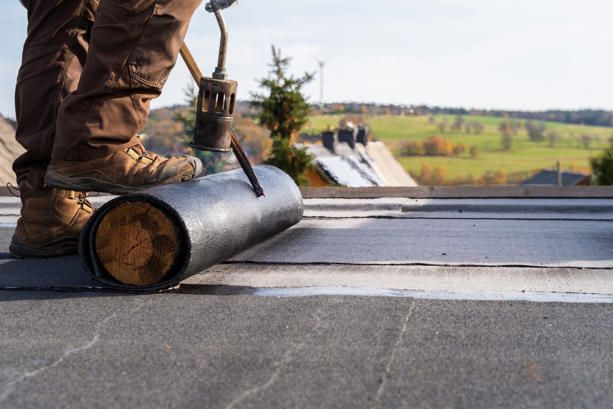Worker Heating and melting bitumen roofing Flat roof installation.