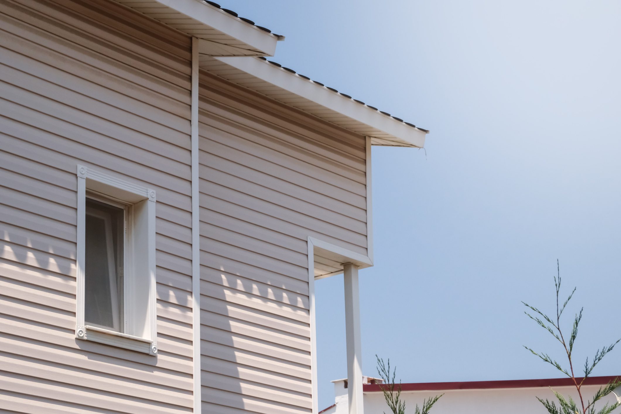 The facade of the new house clad with siding, with windows, against the blue sky.