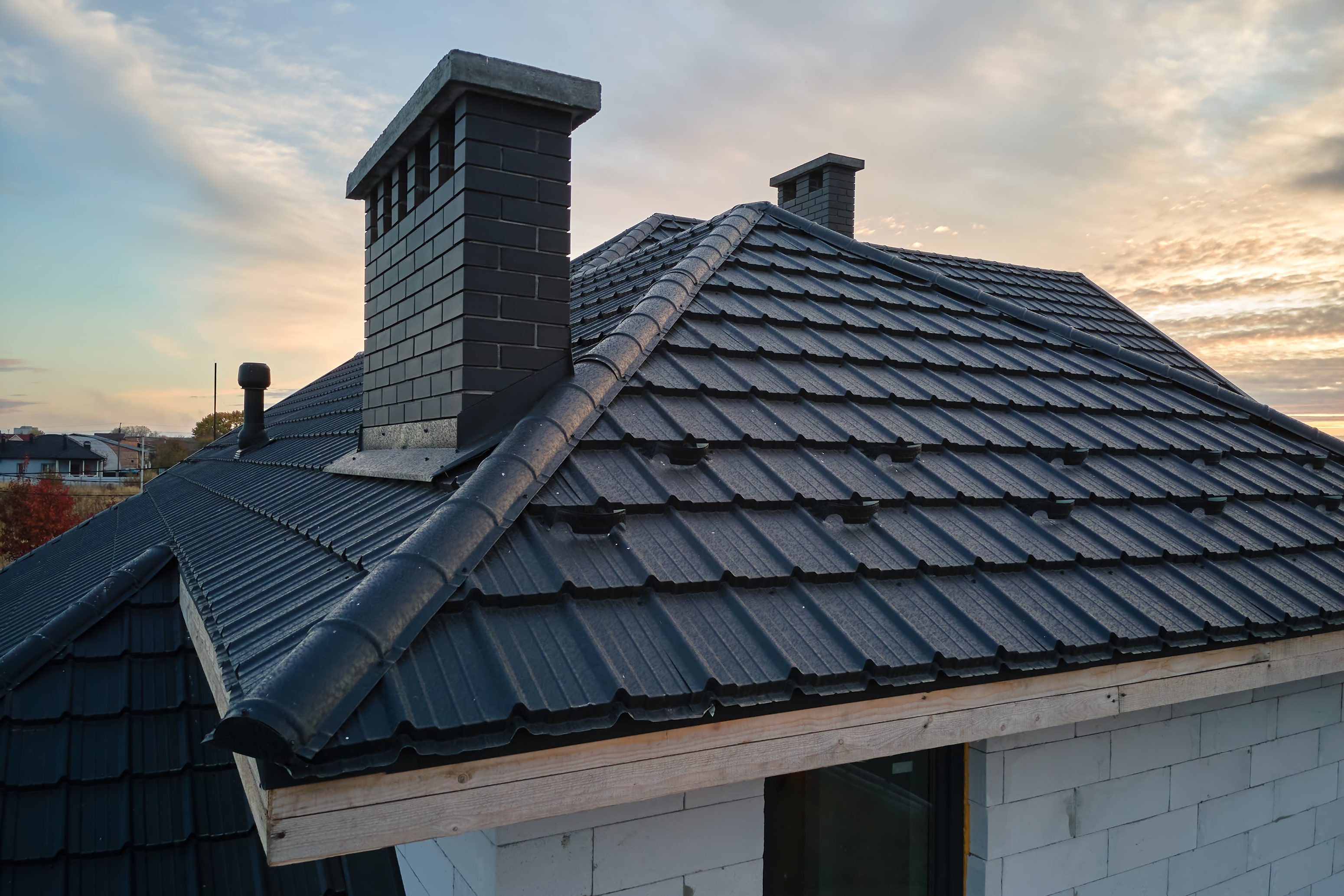 Snow guard for safety in winter on house roof top covered with steel shingles. Tiled covering of building.