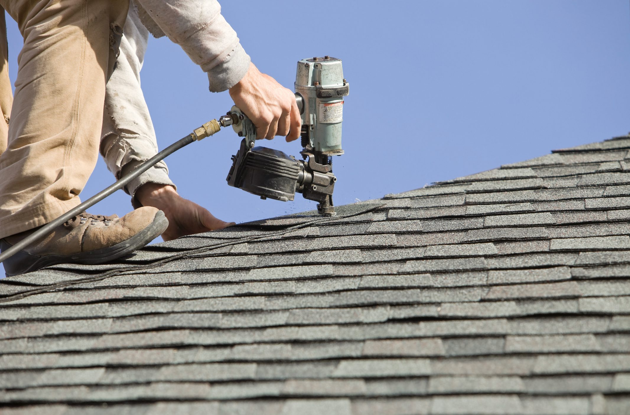 Roofer Nailing Cap Shingle to a New House Roof
