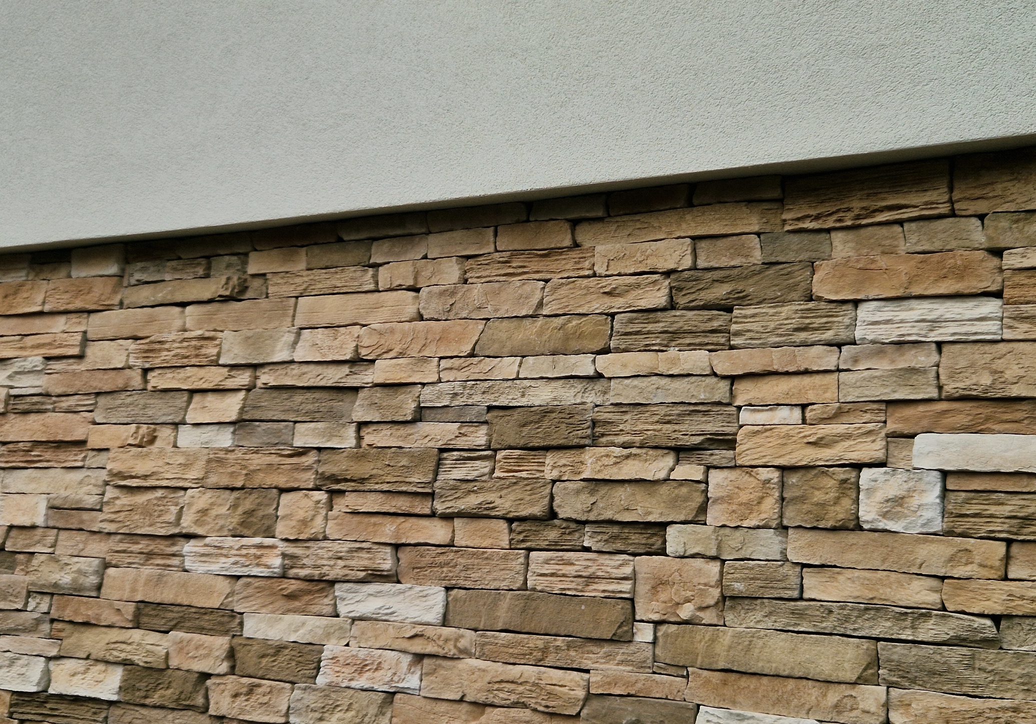 rough,  Modern gray brown, beige, metal door at the house lined with stone cladding. gutter for drainage of water on the pavement. limestone cladding