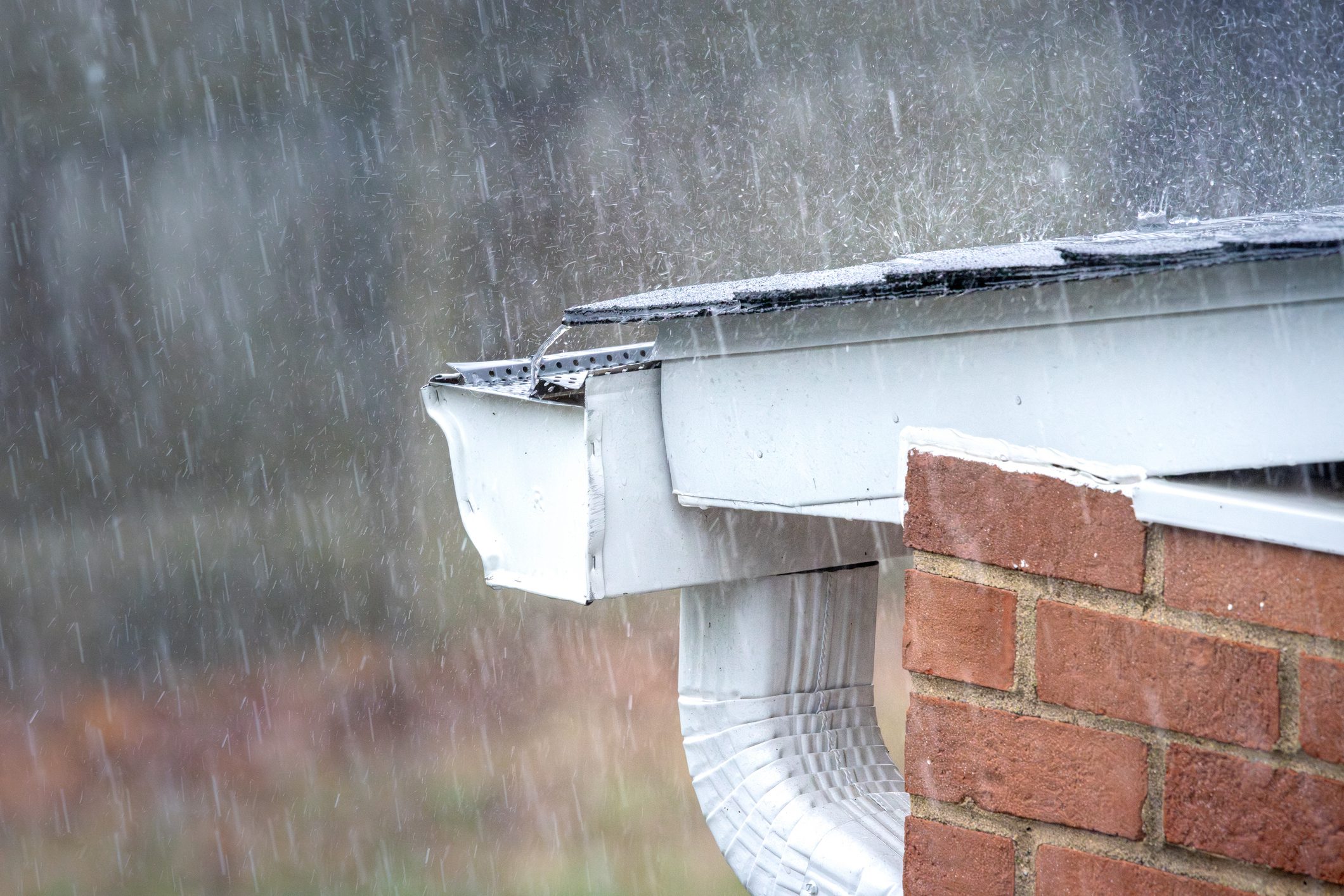 A gutter catches water flowing off roof n a heavy downpour