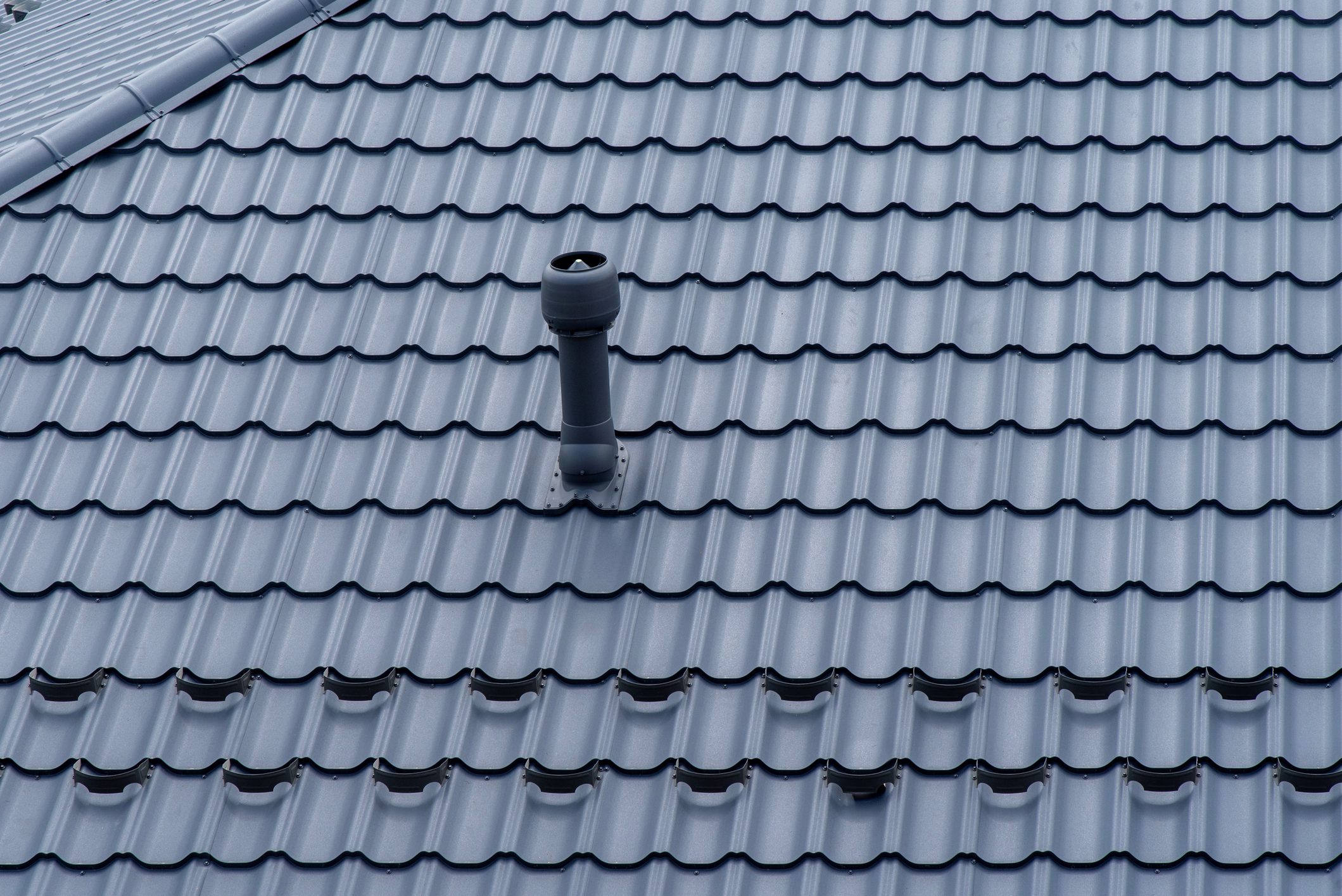 Plastic roof vent pipe on gray metal tile roofing