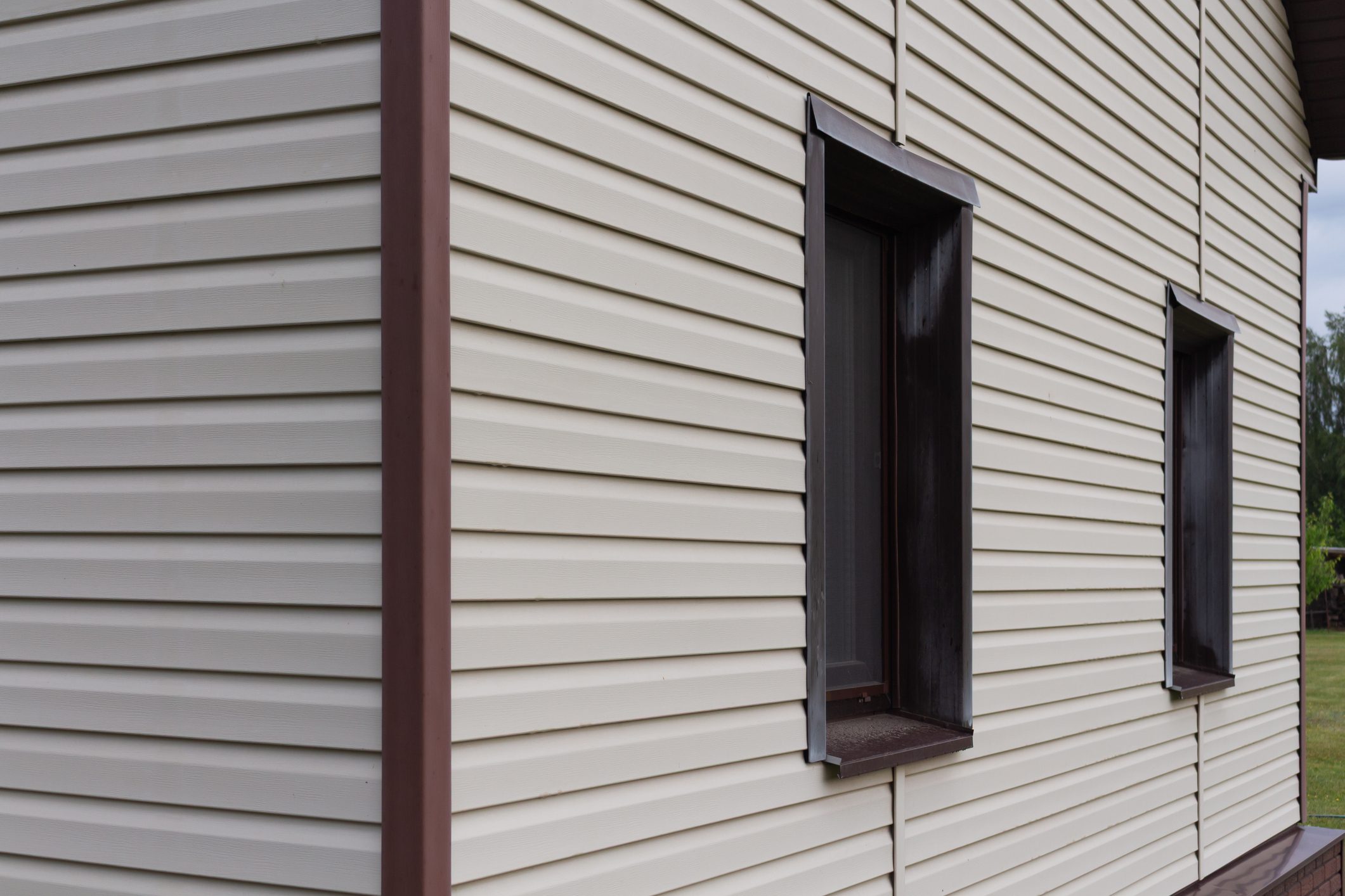 Low angle view of house corner with metal roof and vinyl siding. High quality photo