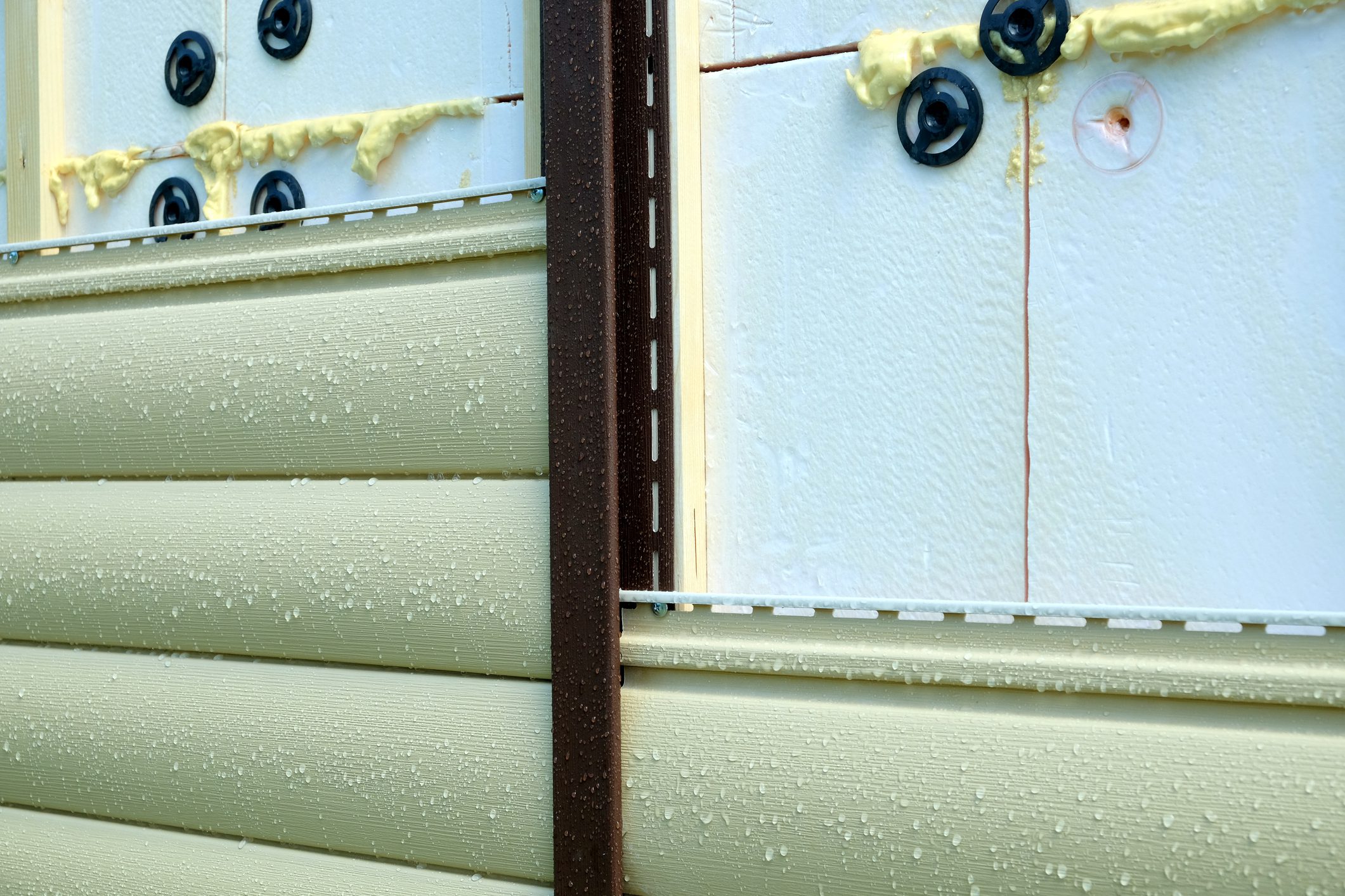 Siding panels mounting over insulation on building wall in rainy day closeup view