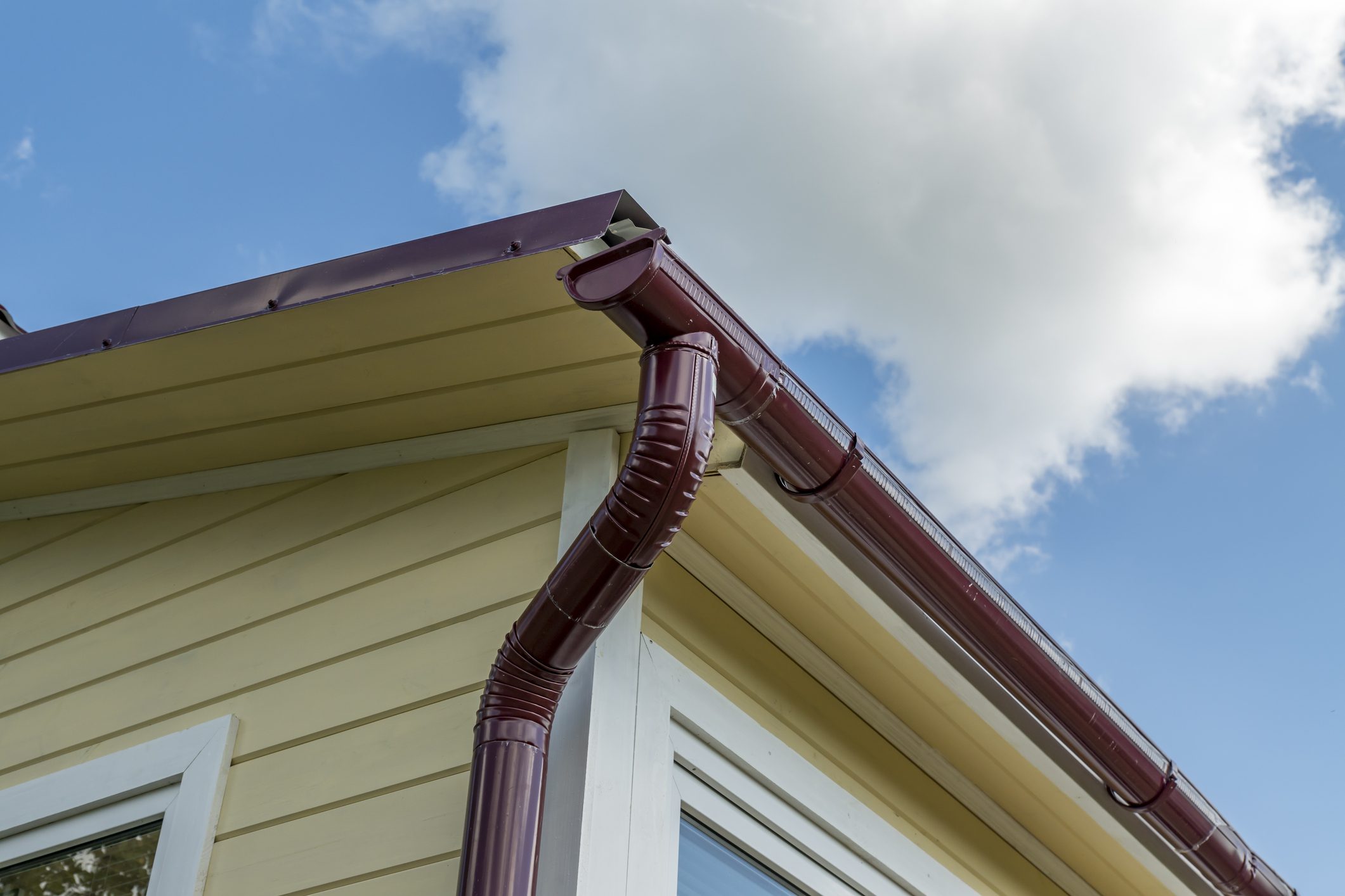 Corner of the house with gutter on a background of blue sky