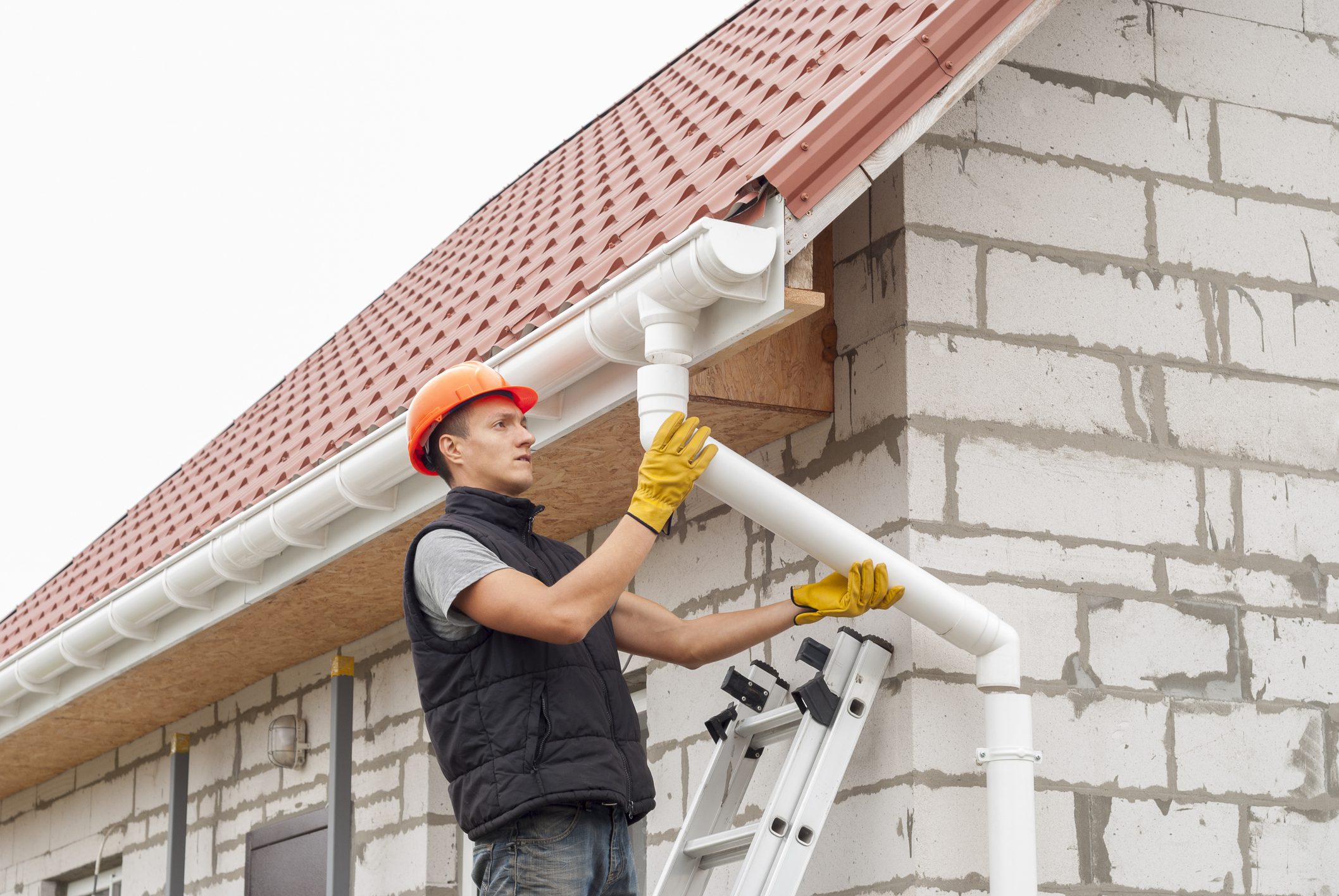 construction worker installs the gutter system on the roof