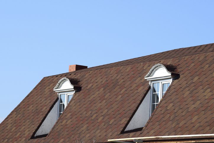A house with a roof made of metal sheets. The house with gables, windows and metal roof, equipped with overflow and protection from snow.