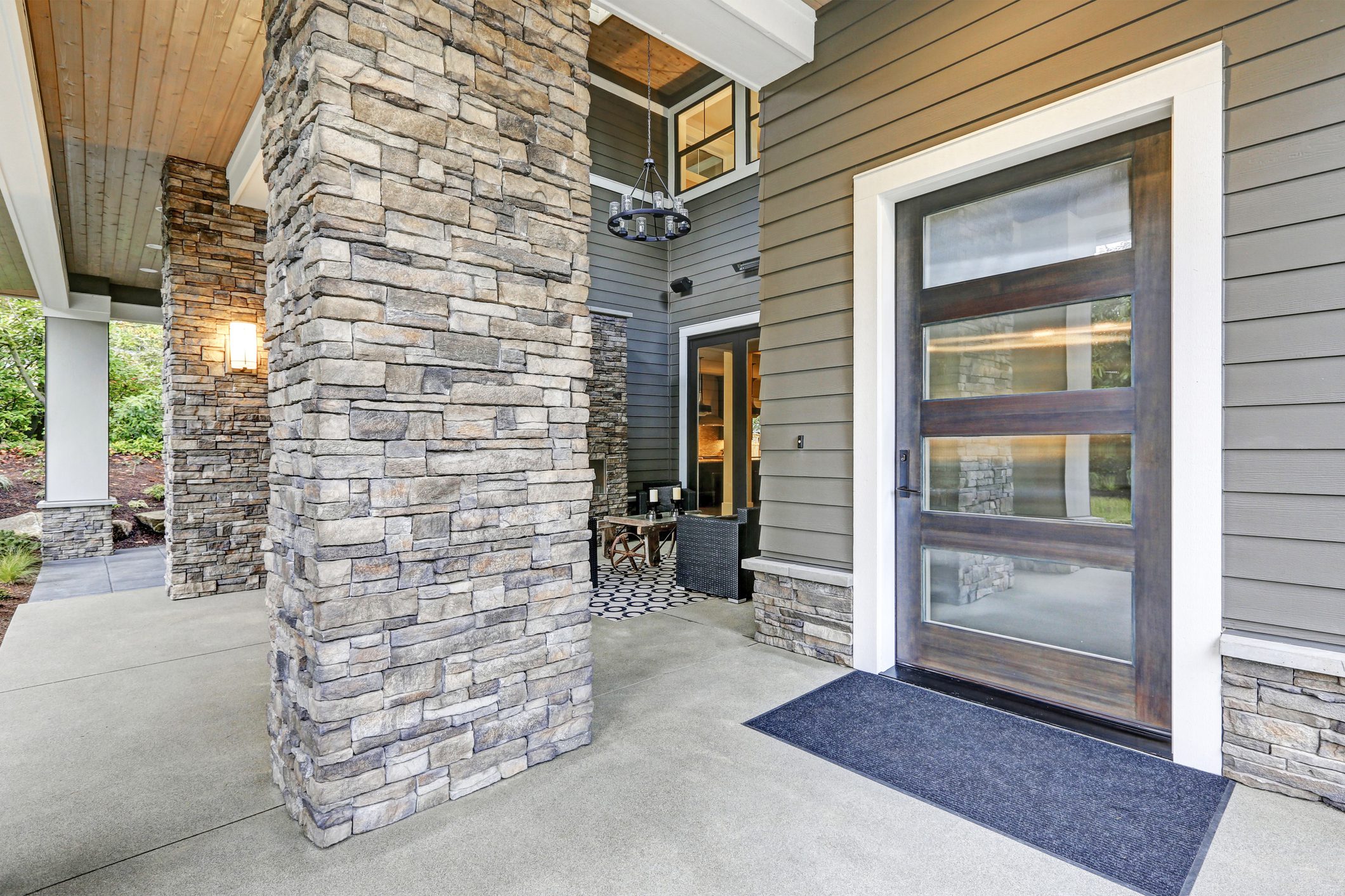 Covered porch accented with stone column and modern glass front door. Northwest, UISA