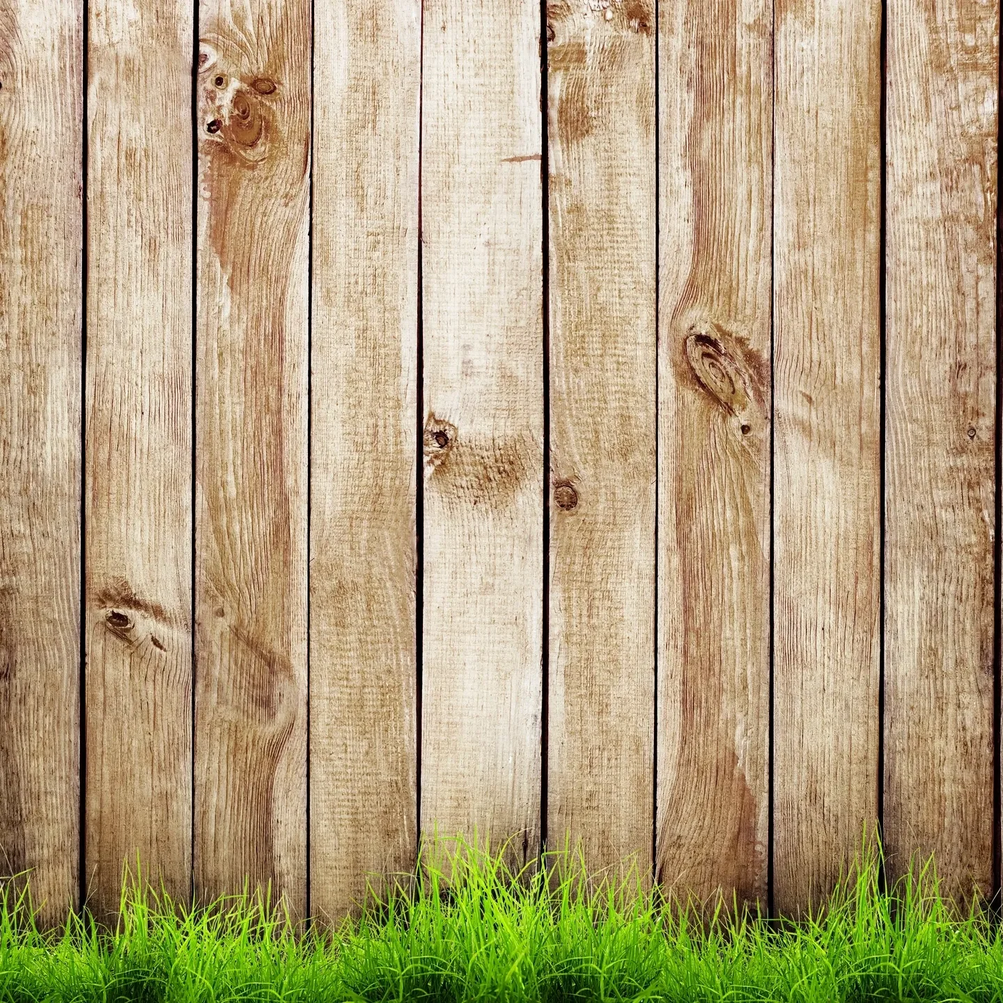 Vertical wooden fence panels with natural textures and knots, bordered by a row of green grass—crafted with a customer-first approach to ensure quality and satisfaction.