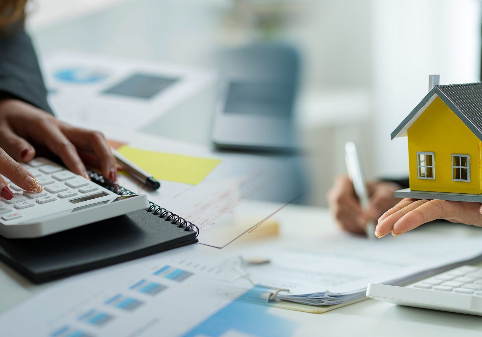 Person holding model house with calculator