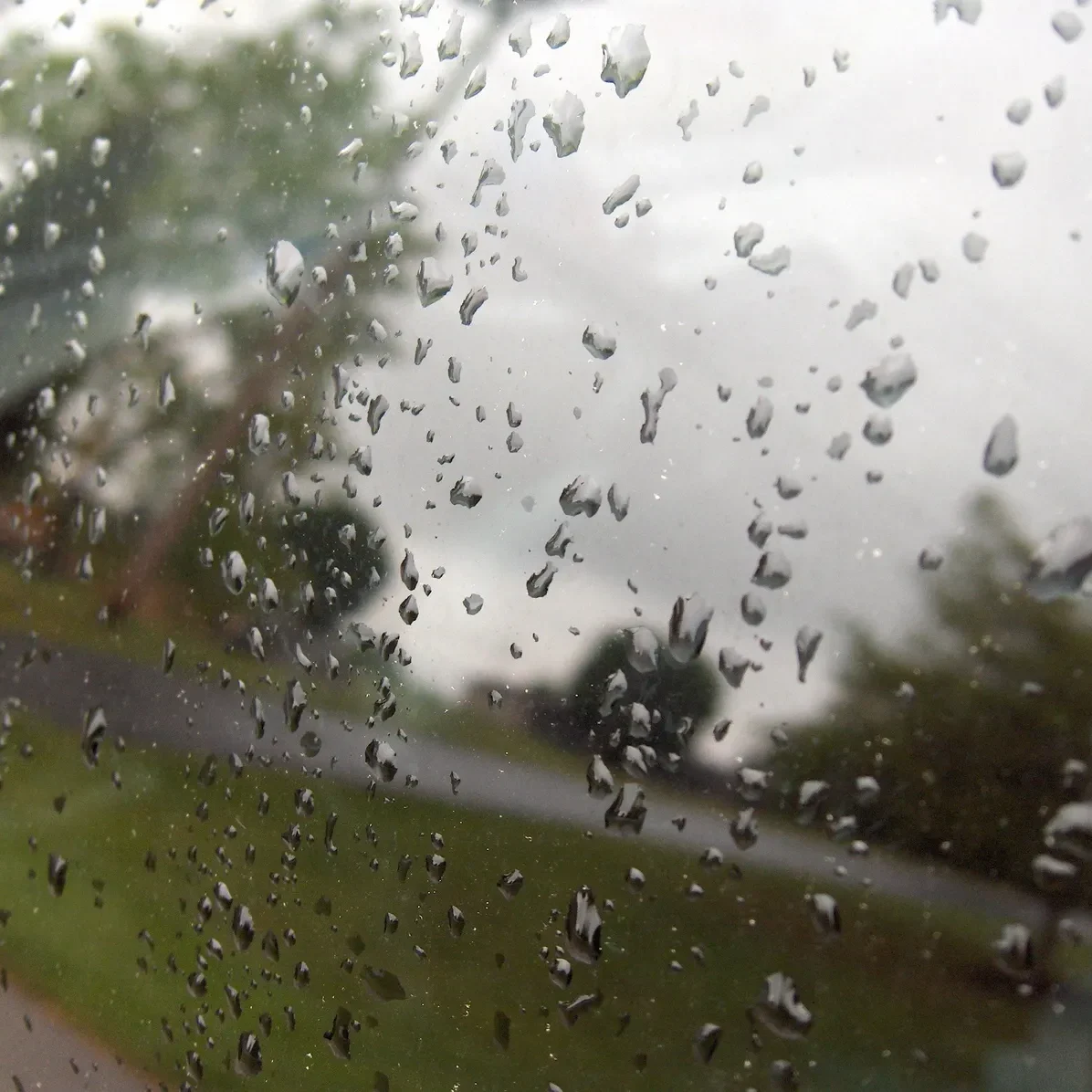 Raindrops on car window with blurred landscape